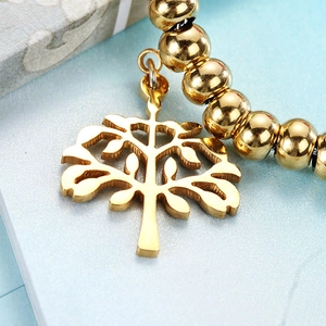 Gros plan du bracelet à perles dorées avec un pendentif détaillé Arbre de Vie