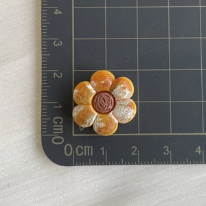 Detailed top view of 2cm miniature flower pastry resin accessory on a grid mat