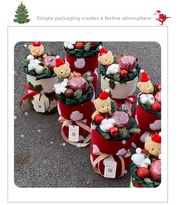 Close-up of Christmas gift box set with plush bear, ornaments, and festive red velvet bucket