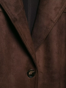 Détail de la texture suédée et du bouton sur la veste marron foncé avec ceinture