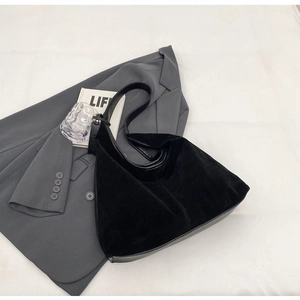 Detail of minimalist black faux suede tote bag on a grey blazer for office styling