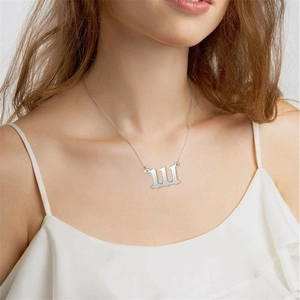 Silver stainless steel gothic letter M necklace worn by model in minimalist setting