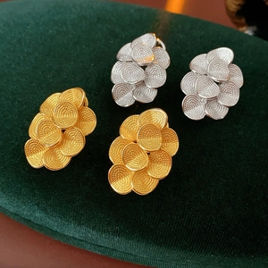 Détail de boucles d'oreilles fleur en or 18 carats et argent sur support velours