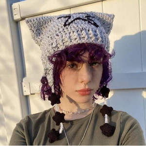 Detail of grey chunky knit cat ear beanie with hanging star tassels and crochet texture