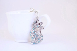 Detailed view of a silver cat keychain with sparkling clear and blue rhinestones