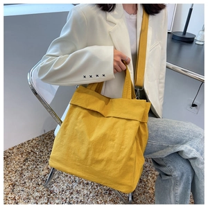Lifestyle view of a spacious yellow nylon tote bag carried by a model in casual attire