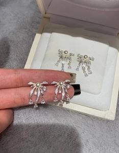 Detail of silver bow tassel earrings with white pearls and sparkling rhinestones