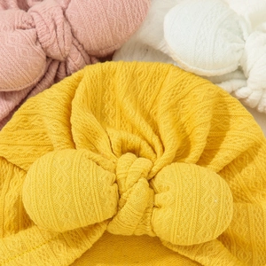 Close-up of baby knit turban hats with large bows and textured jacquard fabric detail