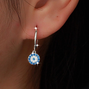 Detail of S925 silver hoop earrings with blue evil eye pendant on a model