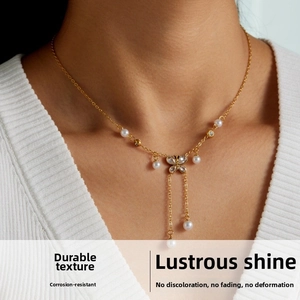 Detailed view of a gold bow pendant necklace with pearls and tassels on a model