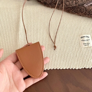 Macro shot of brown faux leather crescent pendant with fine stitching on a woven mat