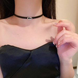 Detailed view of the dark faux leather choker featuring a silver CD letter pendant