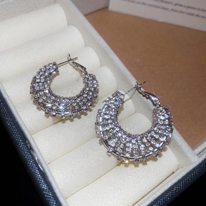 Close-up of sparkling silver hoop earrings with pavé rhinestones in a white jewelry box