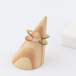 Golden crisscross ring featuring rainbow zircon stones on a wooden display stand