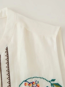 Détail de la broderie florale et géométrique sur un gilet blanc pour femme de style