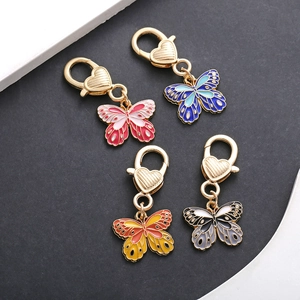 Detail view of four colorful enamel butterfly charms with gold heart-shaped lobster clasps