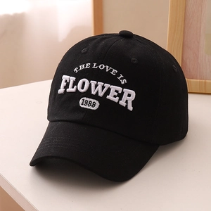 Détail de la broderie blanche en relief sur une casquette de baseball en coton noir