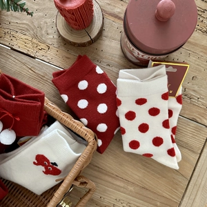 Thick red Christmas knit socks with festive polka dots and cartoon patterns on wood