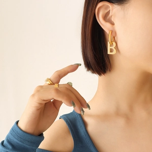Minimalist gold geometric B letter earrings and matching ring on model profile