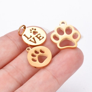 Macro view of tiny gold polished paw print charms with LOVE engraving for DIY jewelry