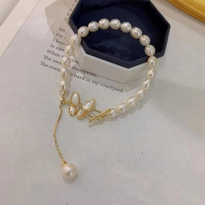 Close-up of freshwater pearl necklace featuring zircon butterfly pendant and gold OT toggle clasp