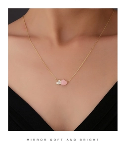 Close-up of elegant double heart necklace in pink and gold on woman's neckline