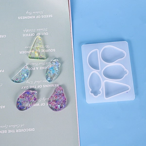 Detalle de moldes de silicona para pinzas de resina con piezas de joyería terminadas