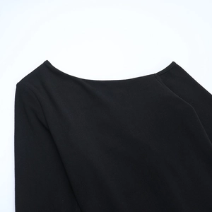Detail view of a black off-shoulder neckline showing fine knit fabric and stitching