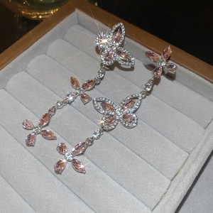 Macro view of pink butterfly zircon tassel earrings on gray velvet jewelry display case