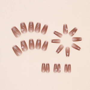 Detail of taupe cat-eye press-on nails with rose gold French tips and pearl accents