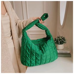 Detail of green quilted puffer handbag featuring a knot-handle design and spacious interior