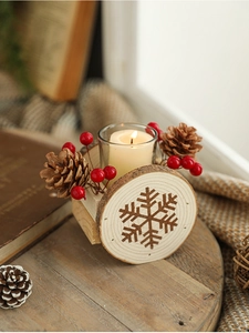 Close-up of wooden Christmas candle holder with pine cones, red berries and snowflake pattern