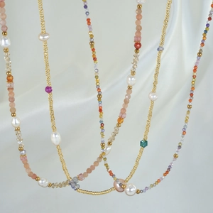 Close-up of layered freshwater pearl and natural stone beaded necklaces on white silk
