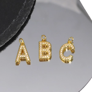 Detail of A, B, C gold letter pendants with inlaid cubic zirconia on a reflective surface
