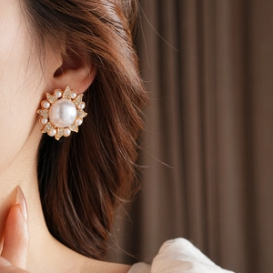 Détail d'une boucle d'oreille vintage en perle tournesol avec strass brillants sur l'oreille