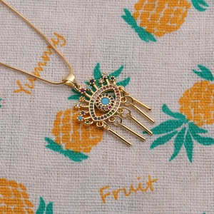 Detail of gold evil eye necklace with colorful zircon stones and four metal tassels