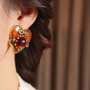 Macro view of vintage resin heart earrings with red gemstone and golden baroque frame
