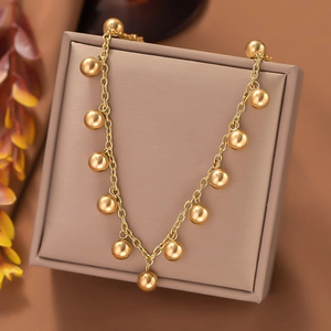 Macro shot of gold layered necklace with polished metal spheres on a jewelry box