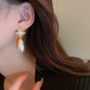 Boucles d'oreilles vintage dorées avec perles goutte portées par un mannequin