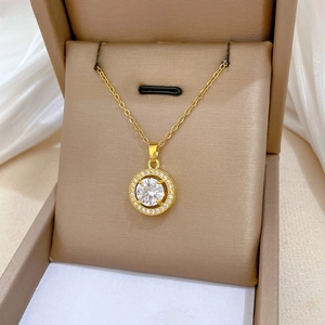 Close-up of gold hollow pendant necklace with white zircon center in a beige gift box