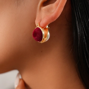 Detail of vintage gold textured metal and red velvet hoop earring on model ear