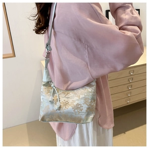 Detail of elegant jacquard shoulder bag with traditional landscape patterns on model