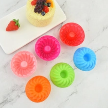 Macro shot of colorful spiral silicone cake molds with a decorated finished cake on marble