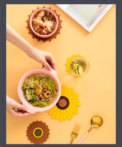Macro shot of sunflower shaped silicone heat resistant table mats with a pink ceramic bowl