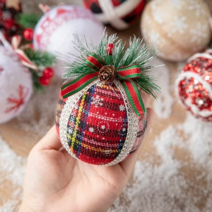 Handheld red and yellow plaid Christmas ornament ball with pine cones and green ribbon bow