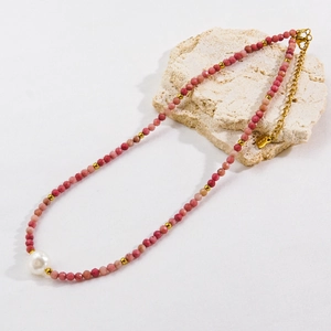 Macro detail of natural faceted stones and baroque pearl necklace on a textured stone