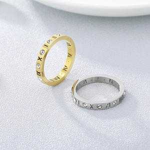 Close-up of polished 18k rose gold and silver rings with Roman numerals and crystals