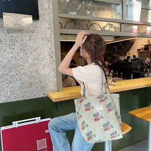 Detail of green corduroy tote bag with Keep Smiling print and logo patch in a cafe setting