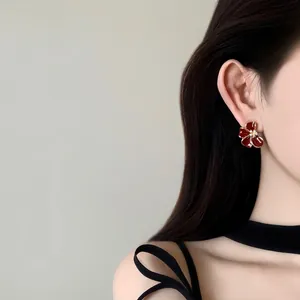 Élégantes boucles d'oreilles fleurs rouges plaquées or 18 carats portées par un mannequin