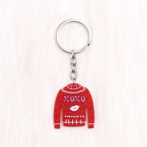 Détail du porte-clés pull à paillettes rouges avec imprimé XOXO sur surface en peluche